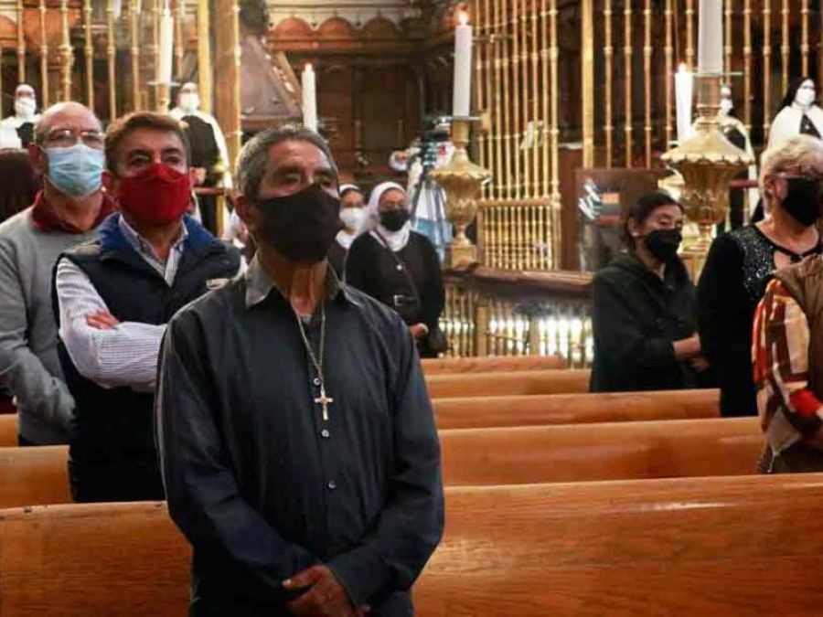 Fedeli in chiesa che portano correttamente la mascherina.